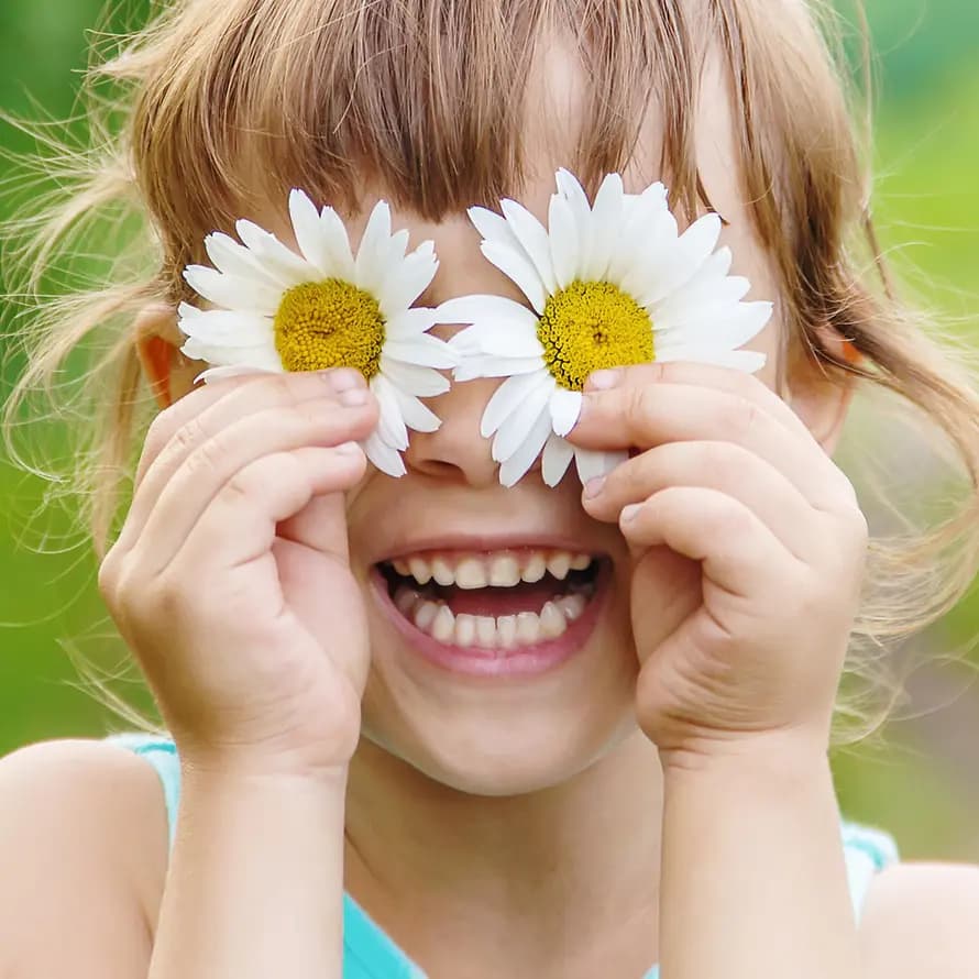 Kind mit Gänseblümchen vor den Augen.
