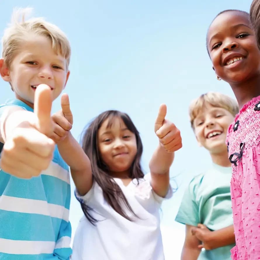 Kinder lachen und halten die Daumen hoch.